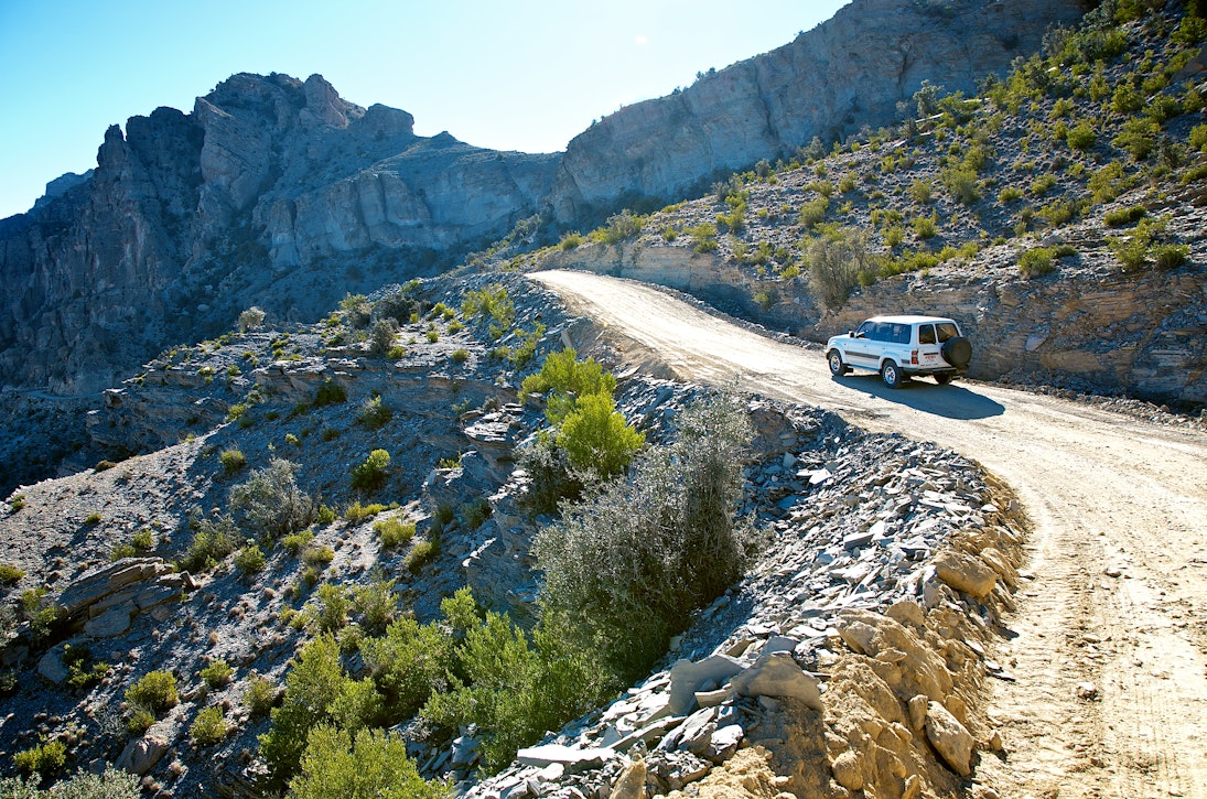 Car climbs dirt track in Wadi Bani Awf (Snake Gorge), Oman.