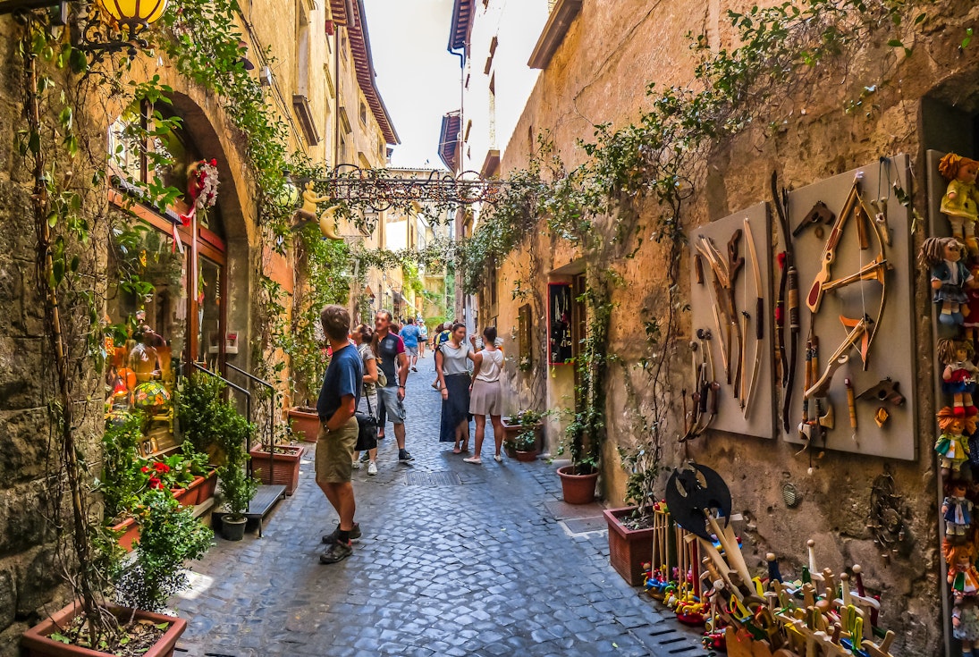 Visitors in a plant-covered lane with ancient buildings near the Cathedral of Orvieto (Duomo di Orvieto).