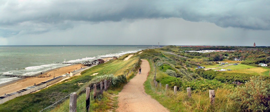 The Westkapelse Zeedijk forms part of the dutch coastal flood defense system. This modern dike, with a layer of basalt stones covered with sand and grass, protects he whole island of Walcheren against coastal floods. Modern flood protection measures allow for recreational and economic activities and development of a natural environment. Picture is taken on a stormy day in summer when a thunderstorm is approaching.