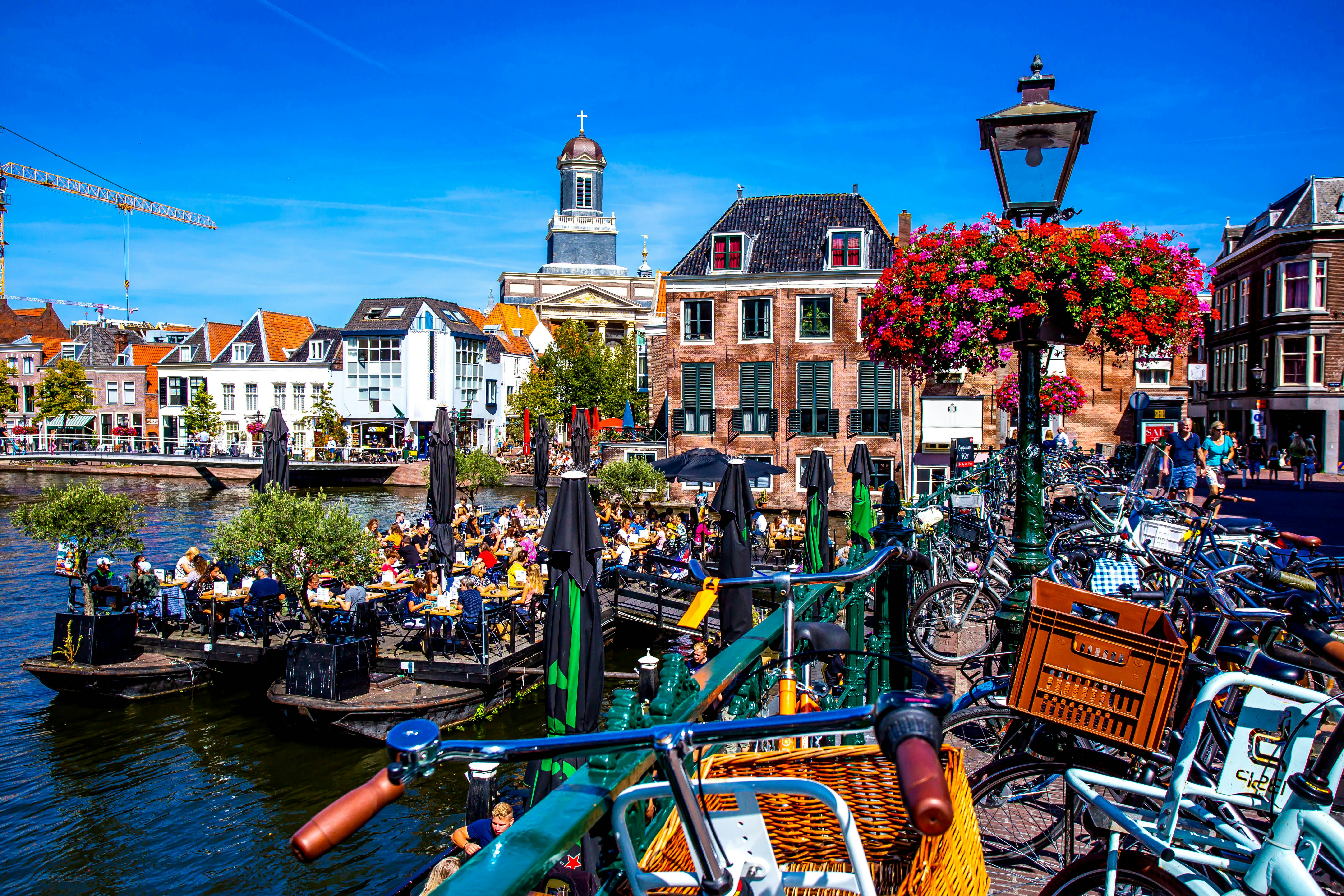 People on a floating barge with drinks in a canal in central Leiden, South Holland, Netherlands