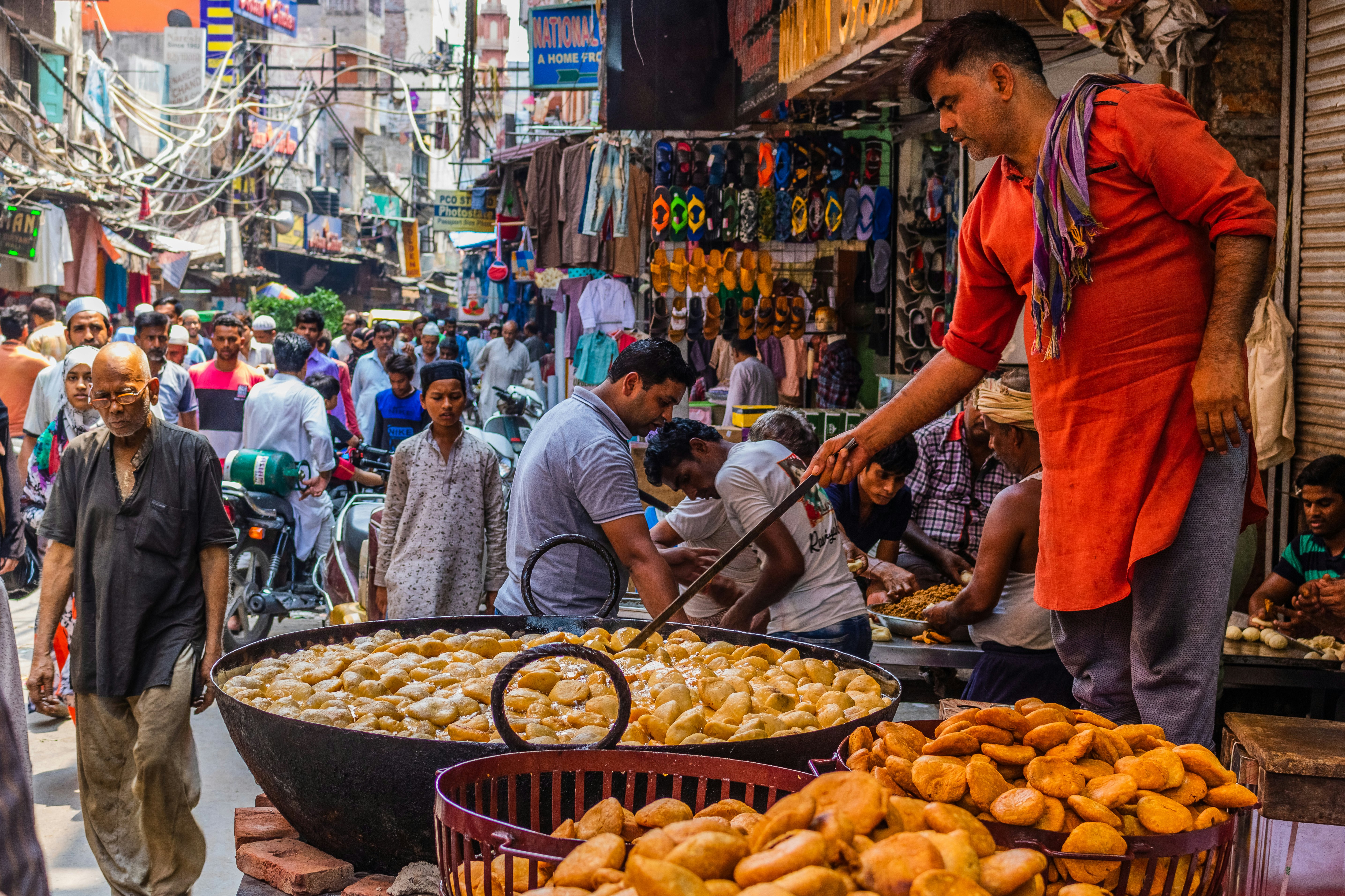 A street-food vendor preparing fritters in a huge pan