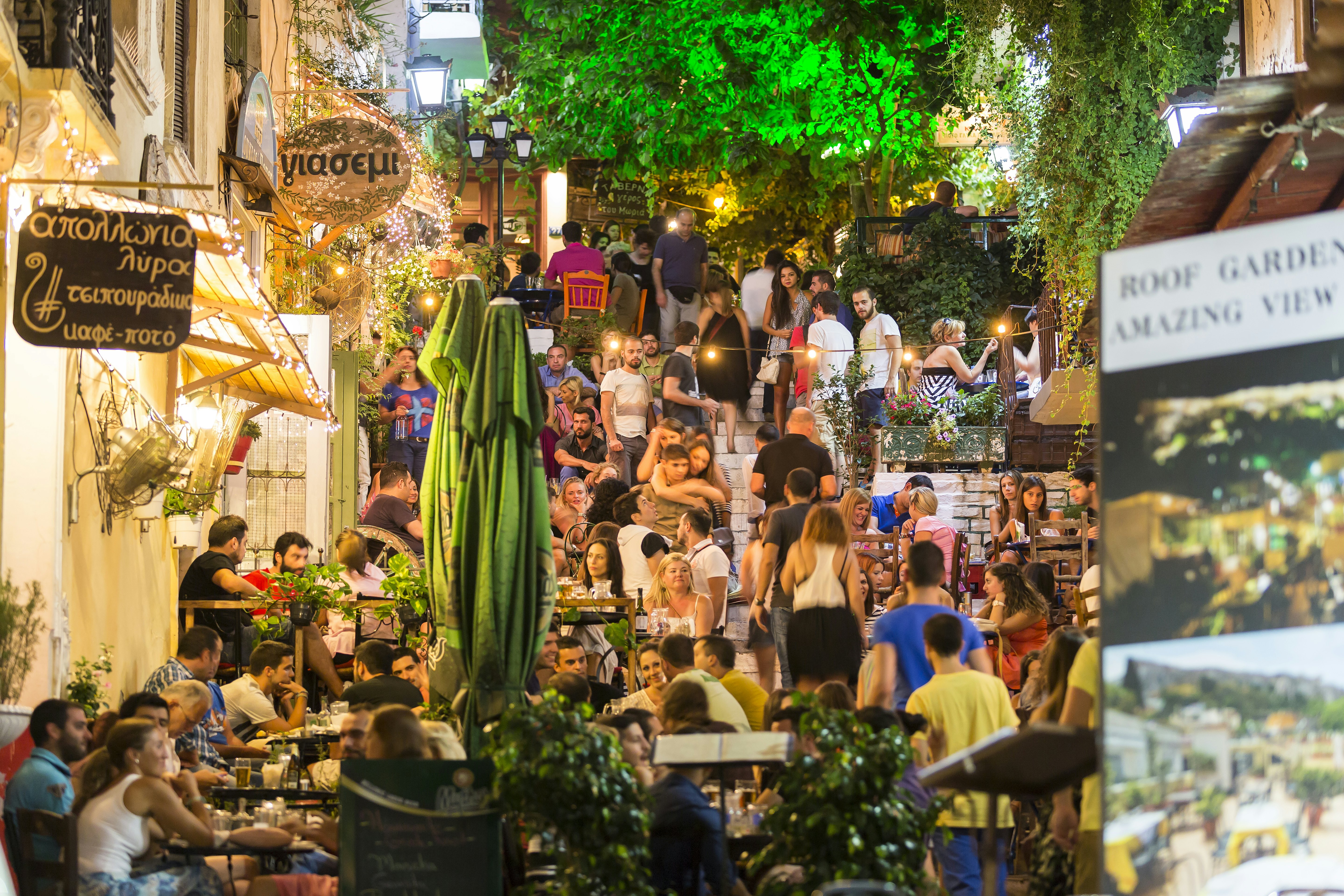 A city street packed with people dining and drinking at outdoor tables.