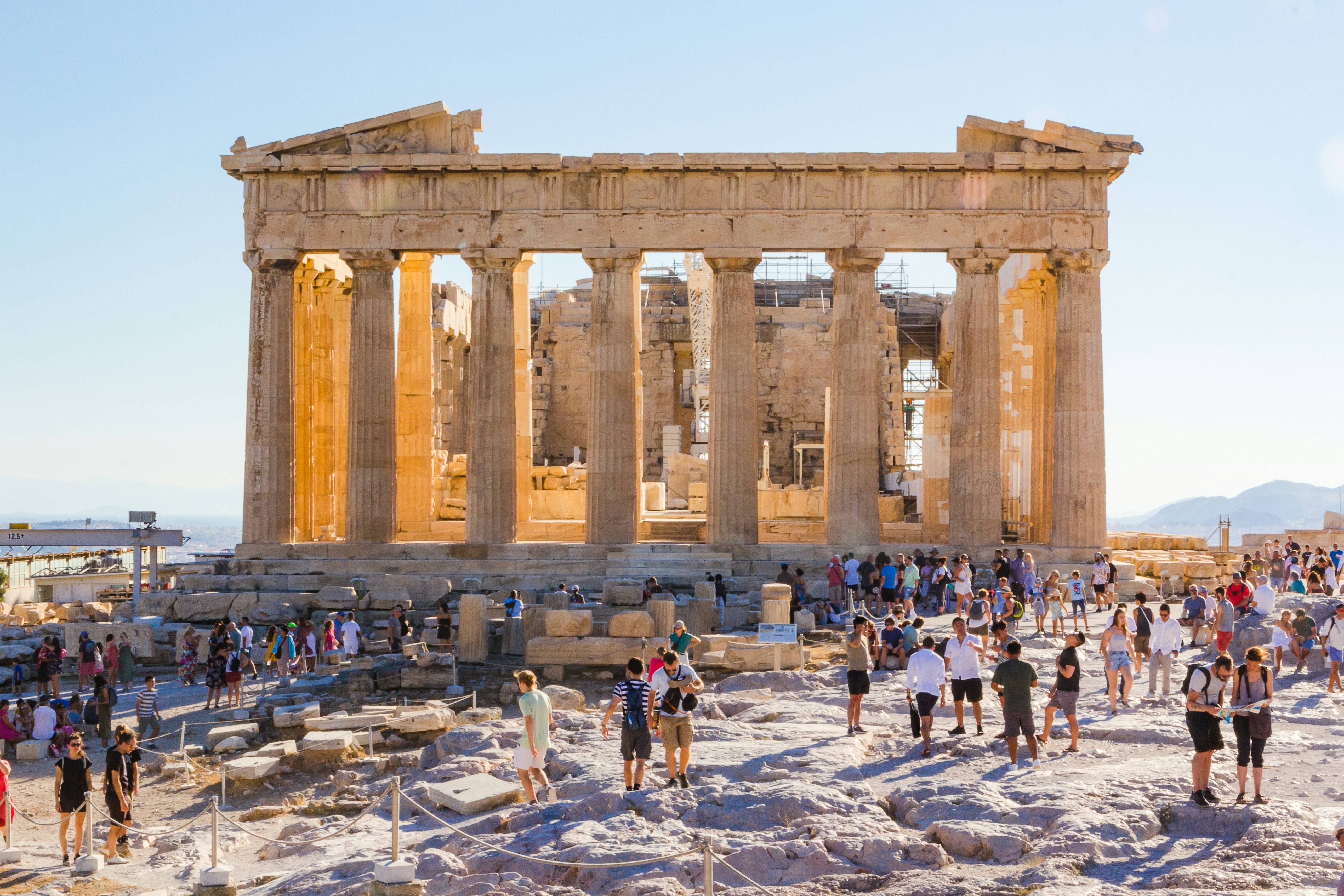 Wide shot of a crowd of tourists outside the Parthenon at sunset.