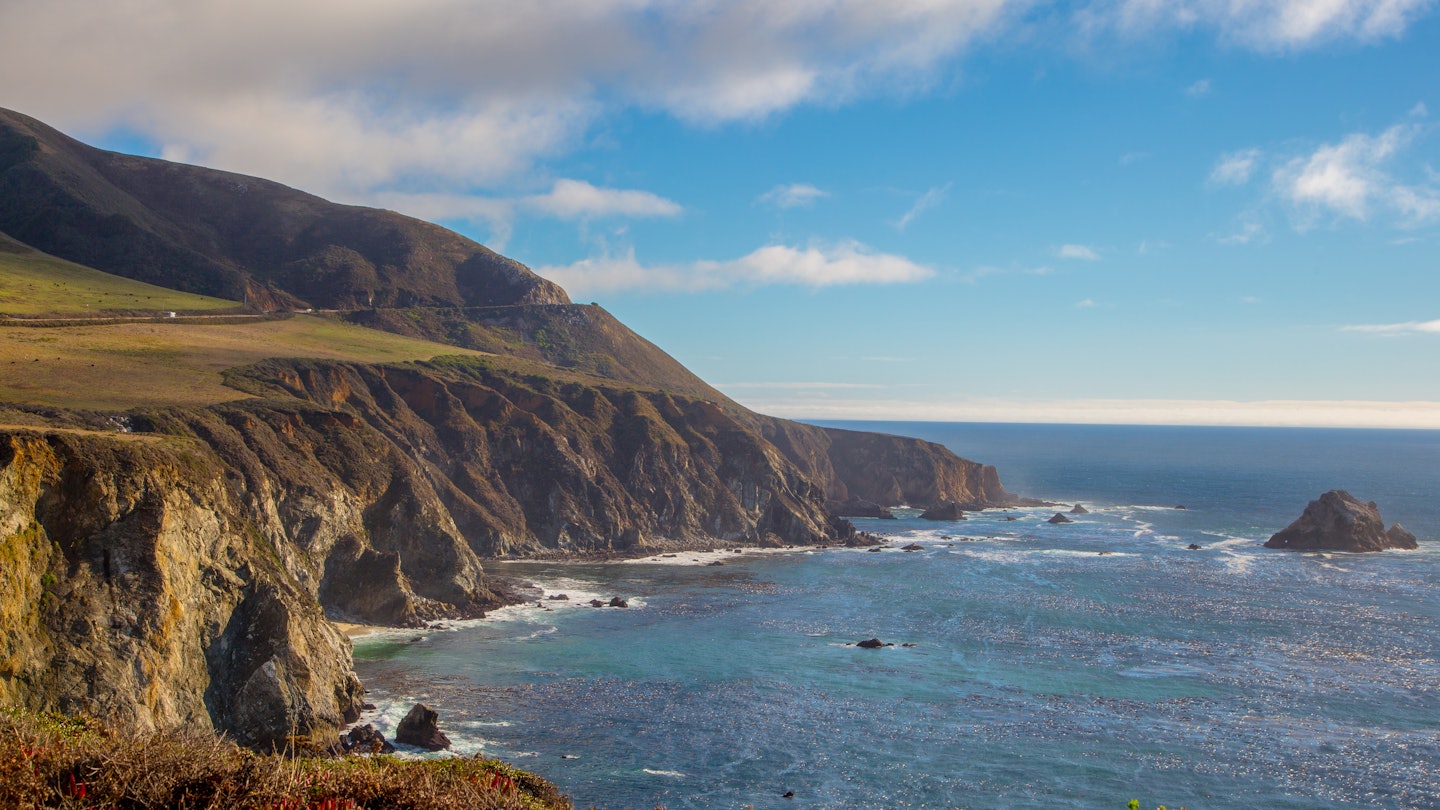 Highway one snakes around a cliff boarding the pacific ocean